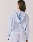 Back view of woman wearing the Abilene Light Skyway Blue Zip Up Hoodie with matching pants on a white background