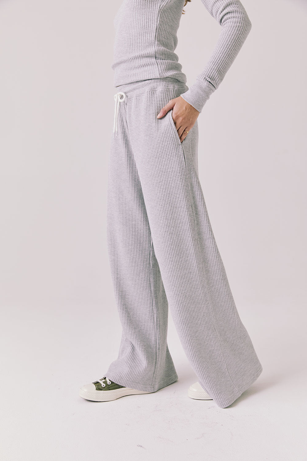 Side view of woman wearing Chaser’s Brandy Light Heather Grey Joggers on a white background