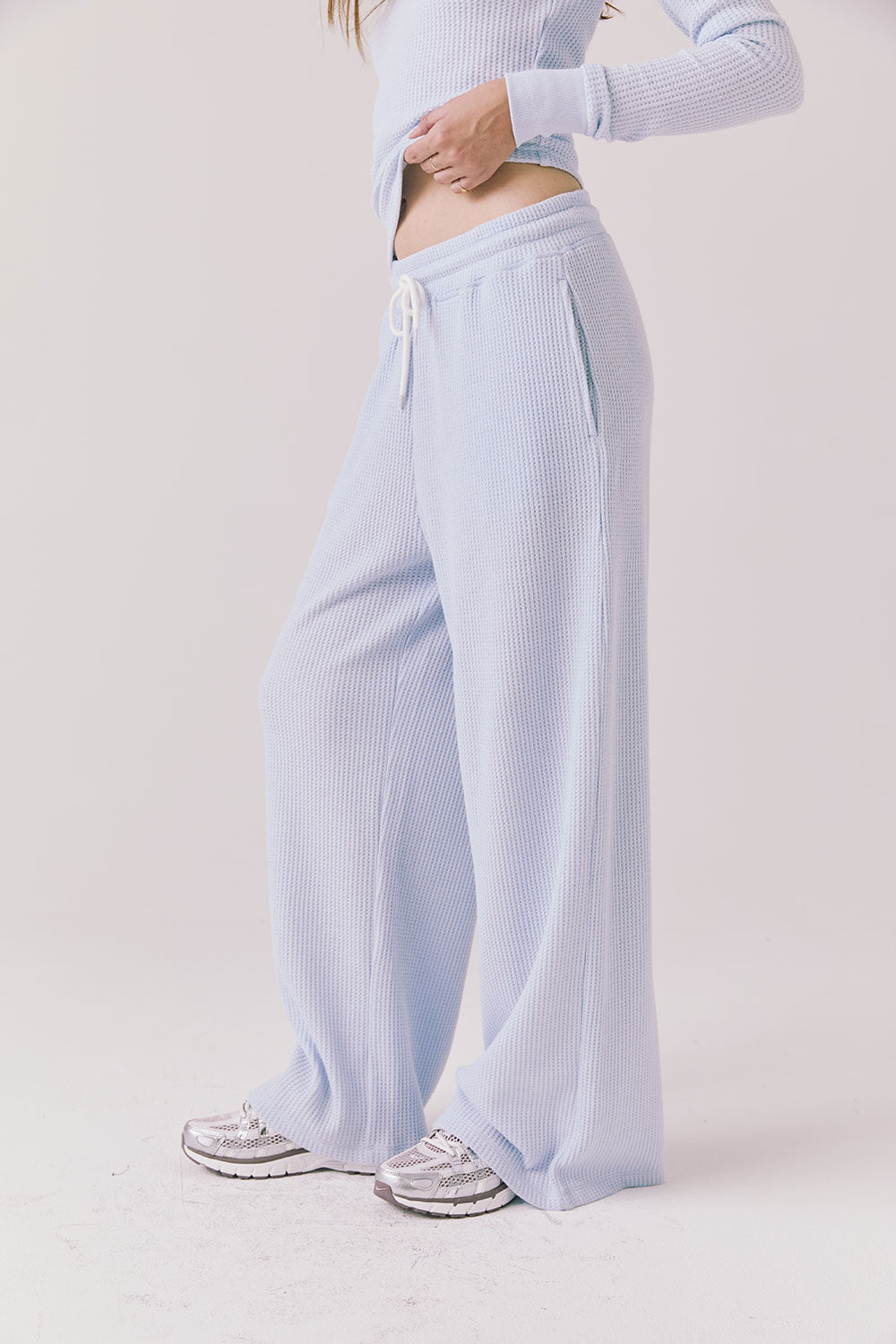 Side view of woman wearing Chaser’s Brandy Skyway Blue Joggers on a white background