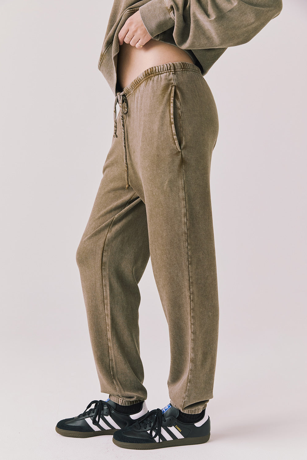 Side view of woman wearing Chaser’s Ginger Brown Manhattan Joggers on a white background