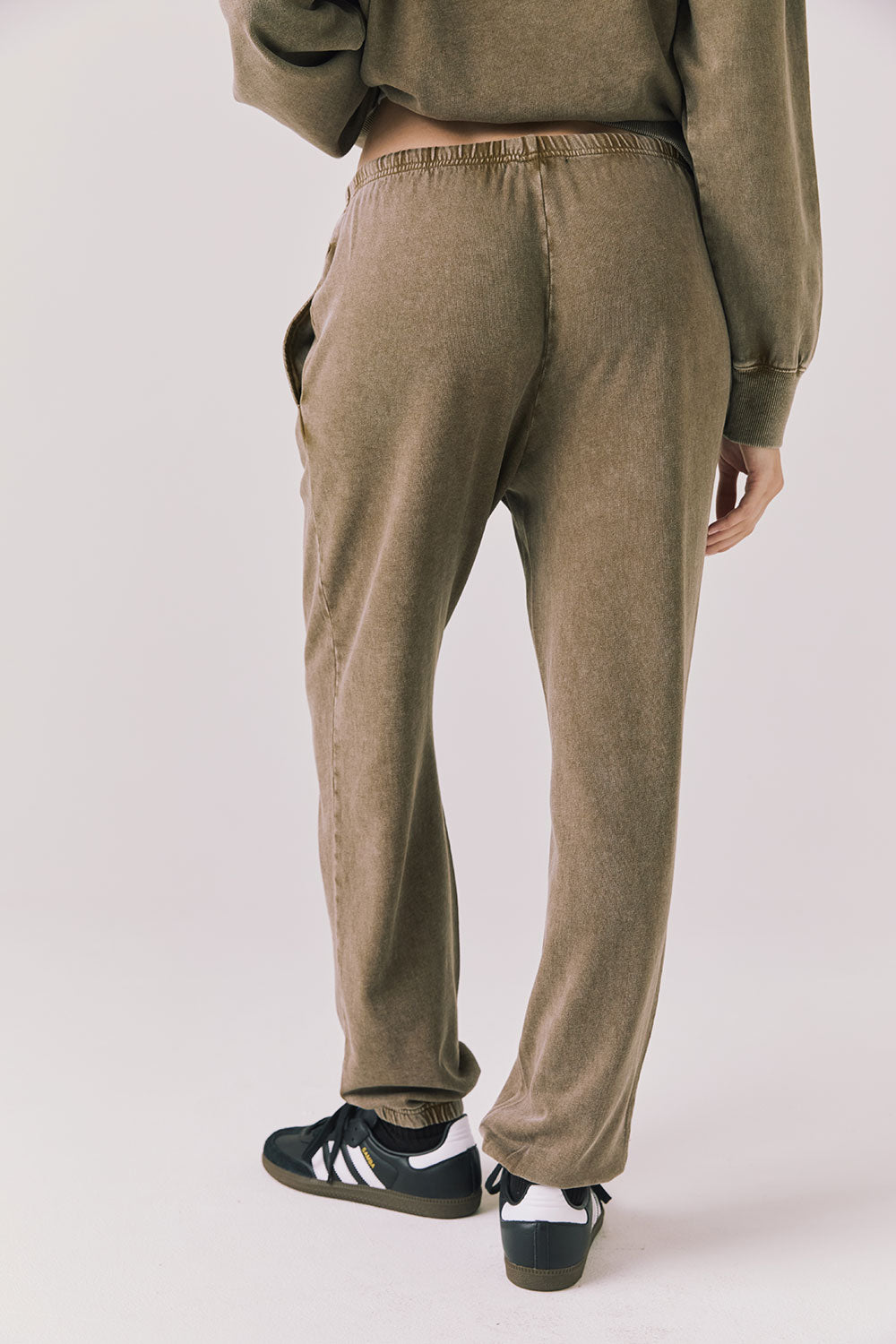 Back view of woman wearing Chaser’s Ginger Brown Manhattan Joggers on a white background