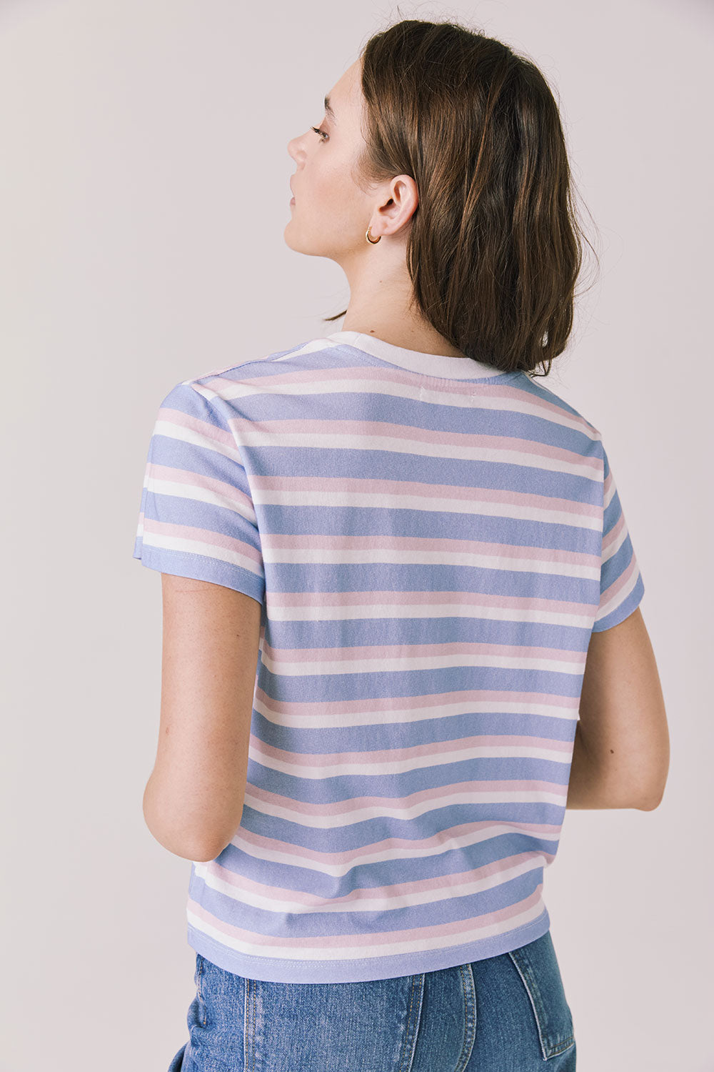 Back view of woman wearing Chaser’s Cosmo Pink Stripes Tee with pink stripe detailing on a white background
