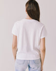 Back view of woman wearing Chaser’s Cosmo White Tee with relaxed fit and light blue jeans on a plain background