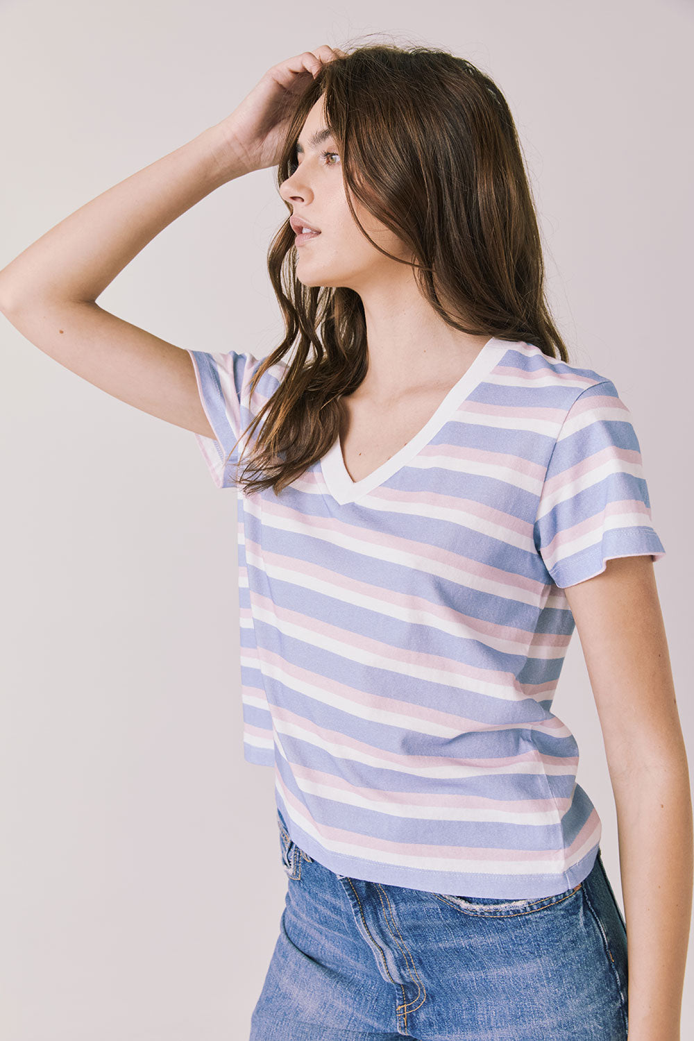 Side view of woman wearing Chaser’s Gimlet Pastel Stripe Tee on a plain background