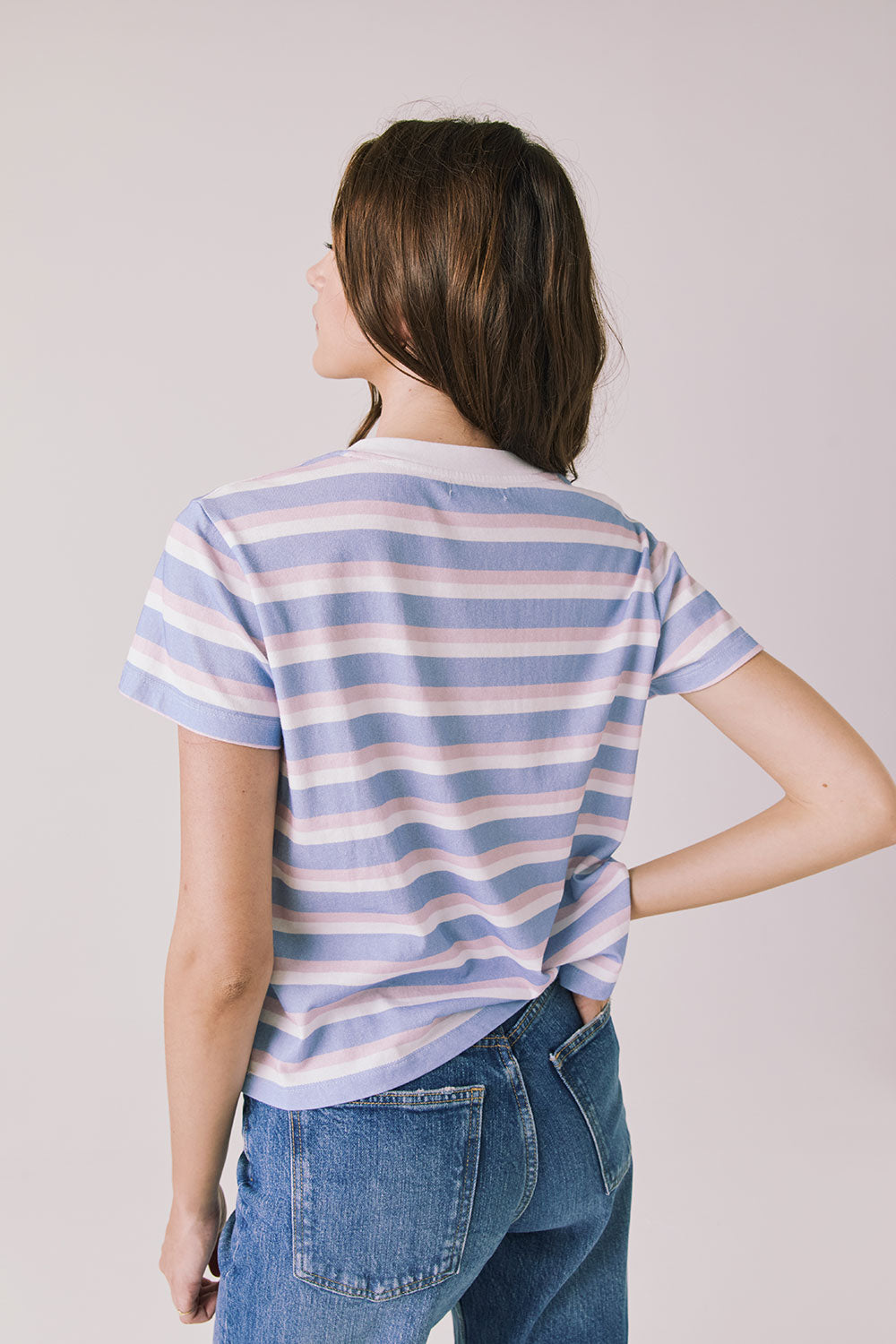 Back view of woman wearing Chaser’s Gimlet Pastel Stripe Tee on a plain background