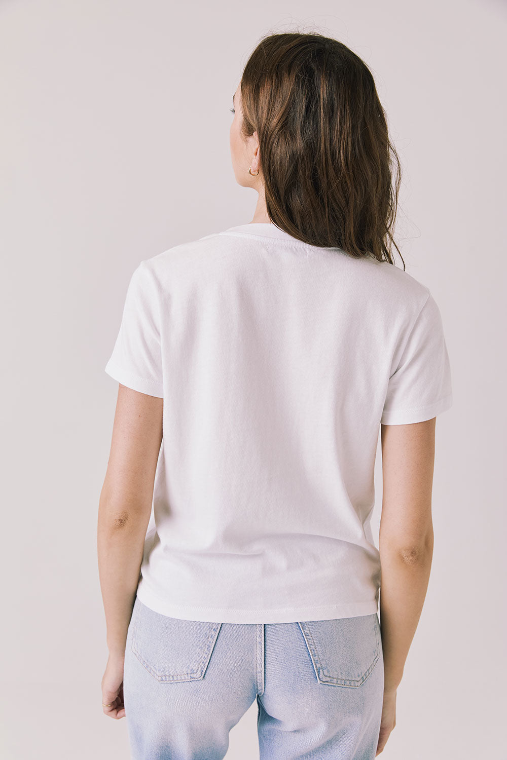 Back view of woman wearing Chaser’s Gimlet White Tee on a plain background
