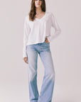 Full body view of woman wearing Chaser’s Whiskey White Long Sleeve paired with blue jeans on a plain background