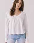 Front view of woman wearing Chaser’s Whiskey White Long Sleeve with classic crew neckline on a plain background