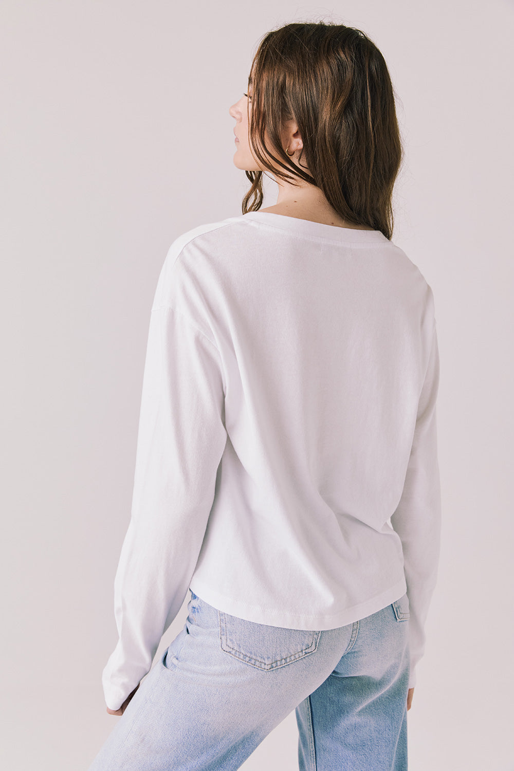 Back view of woman wearing Chaser’s Whiskey White Long Sleeve on a plain background