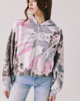 Front view of woman wearing Chaser’s Heart Tie Dye Zip Up Hoodie with heart embroidery on the left chest on a white background