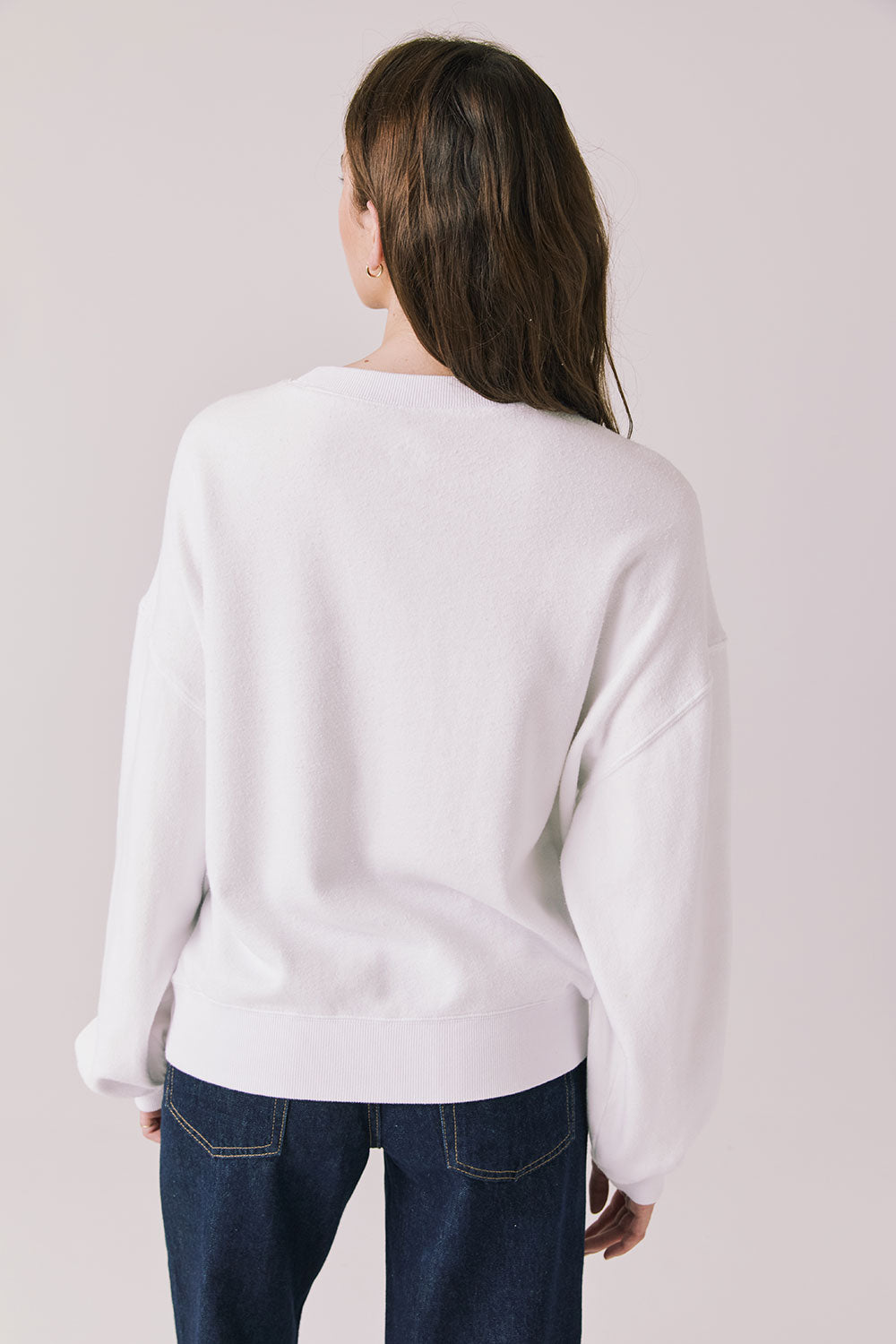 Back view of woman wearing Chaser’s white Vacation Long Sleeve on a light background
