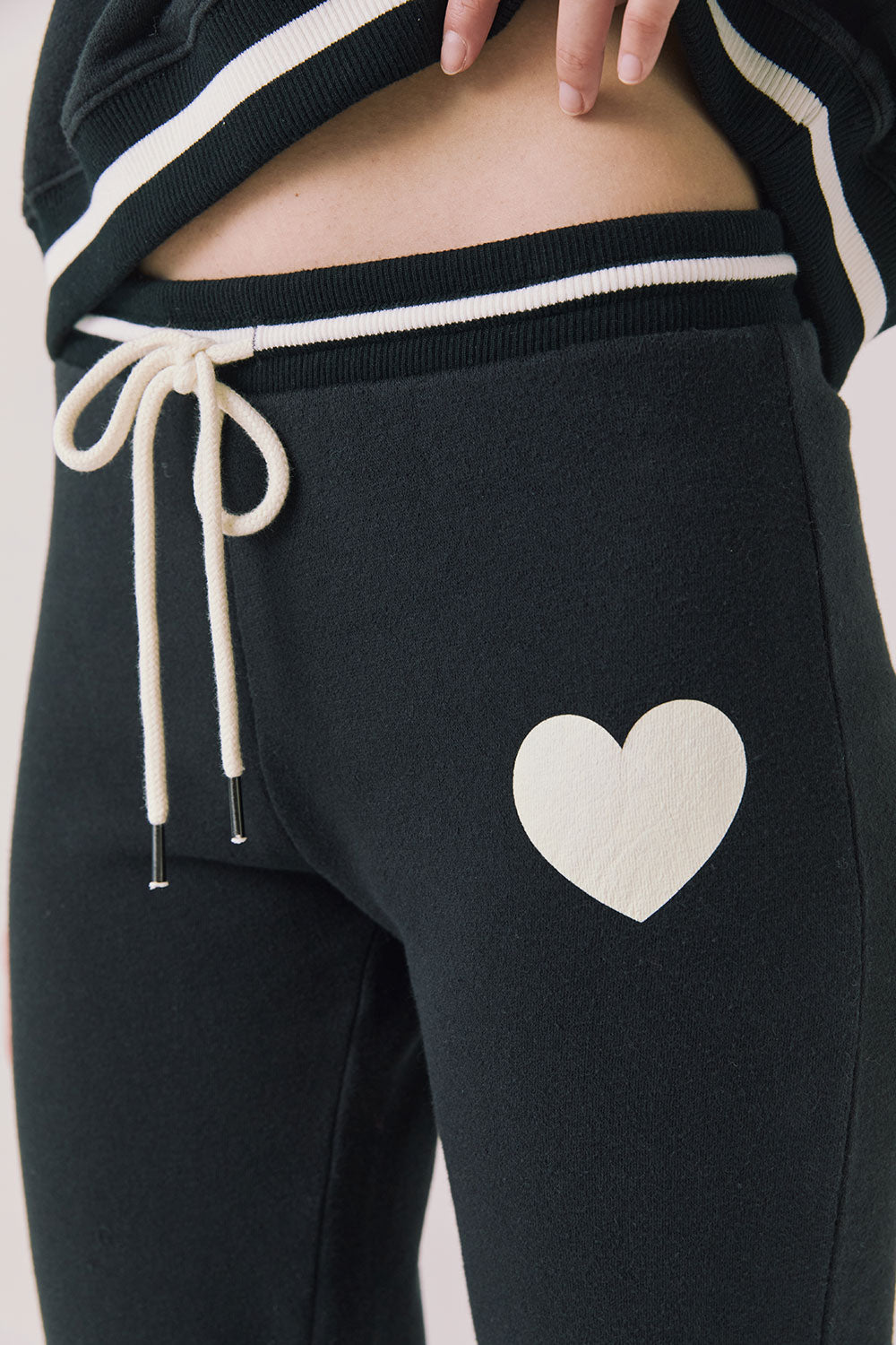Side view of woman wearing Chaser’s Heart True Black Joggers with heart design on a white background