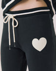 Side view of woman wearing Chaser’s Heart True Black Joggers with heart design on a white background