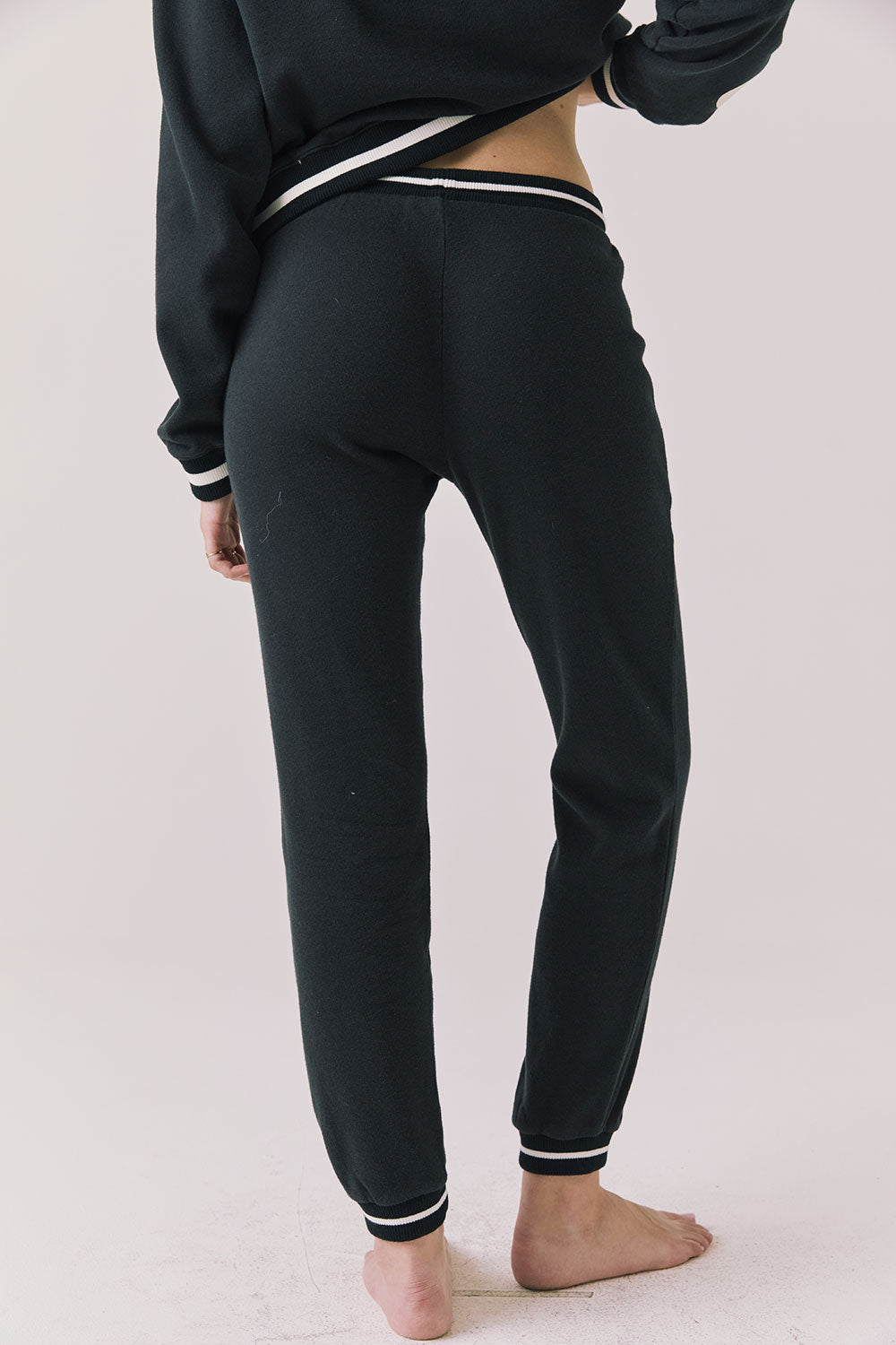 Back view of woman wearing Chaser’s Heart True Black Joggers on a white background