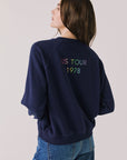 Back view of woman wearing Chaser’s The Rolling Stones US Tour 1978 Long Sleeve in Oxford Blue with tour cities text on a white background