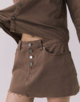 Angled front view of the Chaser Sloane Cognac Wash Mini Skirt showing button fly and relaxed mini silhouette