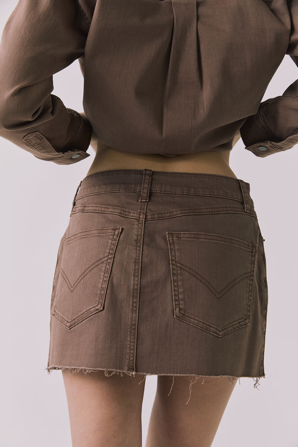 Back view of the Chaser Sloane Mini Skirt in Cognac Wash highlighting pocket placement and raw hem finish