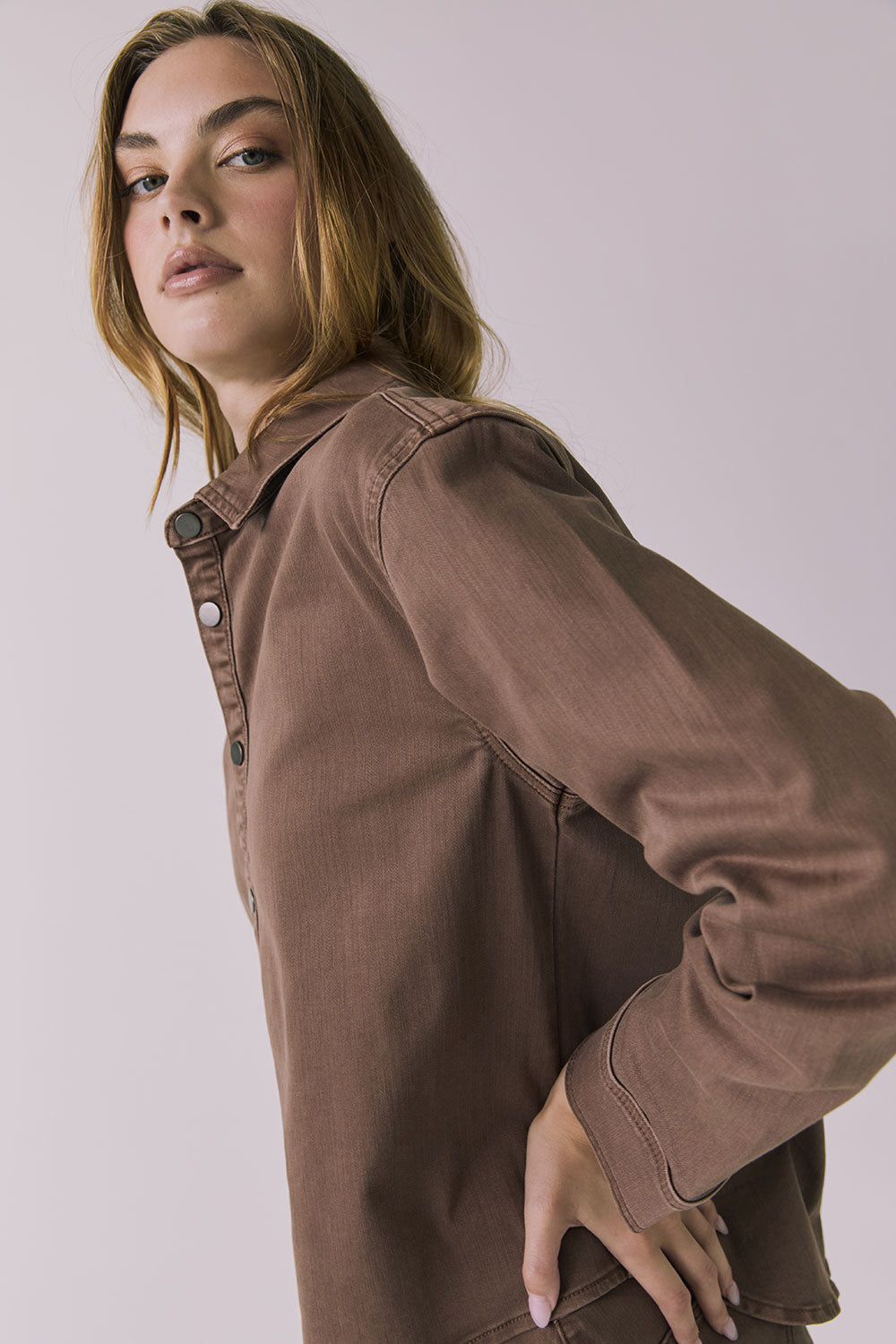 Side view of a woman wearing the Chaser brown All Day Cognac Wash Button Down against a plain background