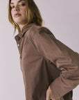 Side view of a woman wearing the Chaser brown All Day Cognac Wash Button Down against a plain background