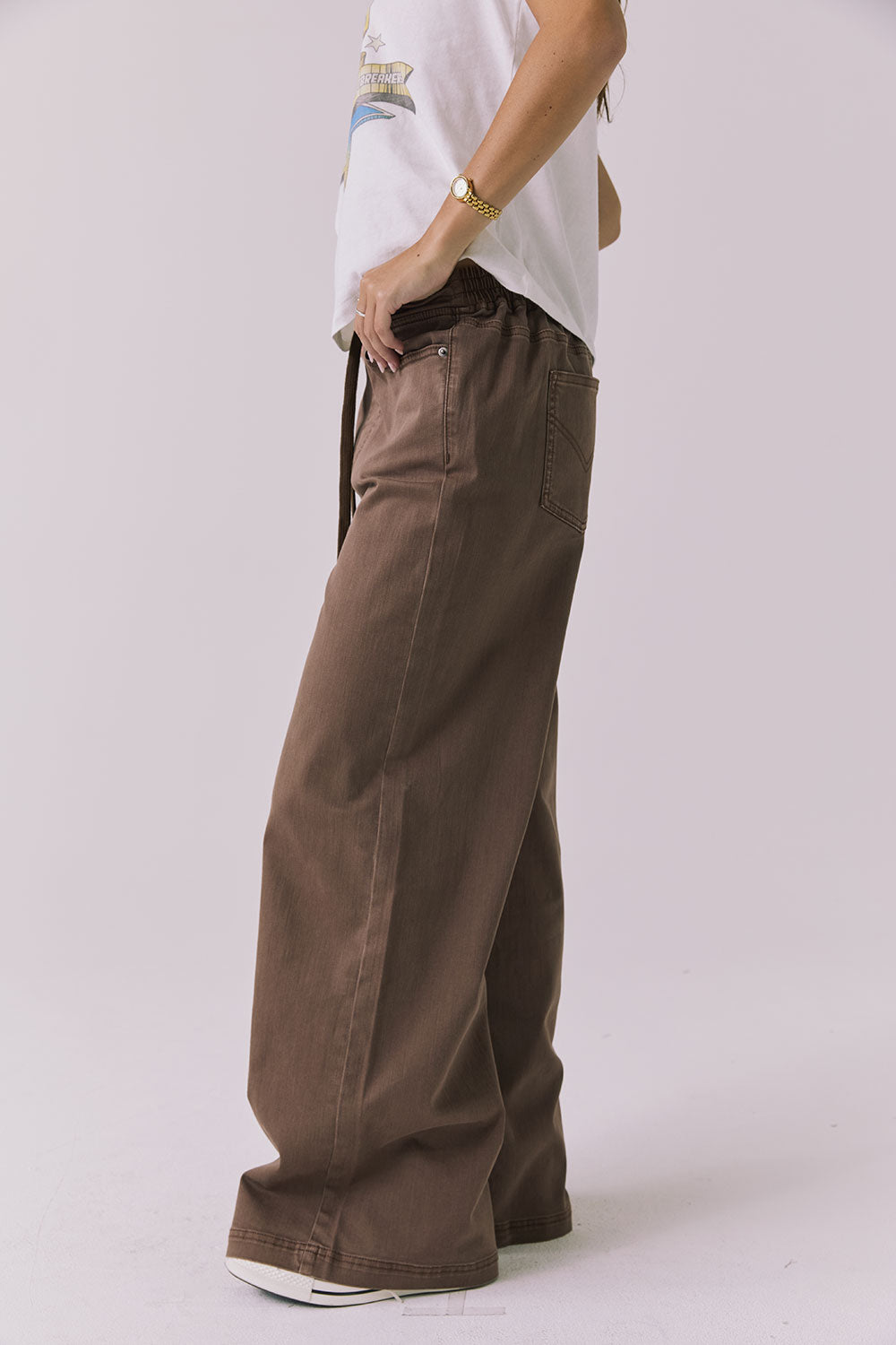 Side view of a woman wearing Chaser's Layover Cognac Wash Jogger against a plain background