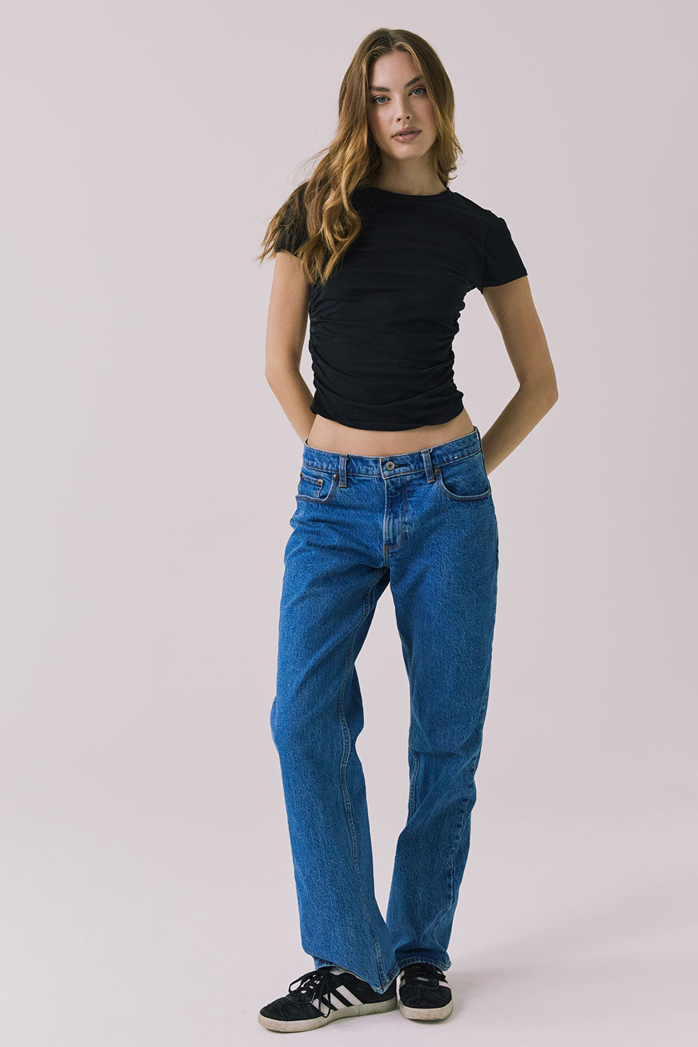 Full body view of the Chaser Louis Black Tee styled with relaxed denim jeans on a plain background