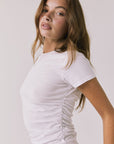Side view of the Chaser Louis White Tee showing the flattering ruched design and slim profile