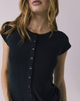 Close up view of a woman wearing the Chaser Anchor Black Tee with buttons and blue jeans against a plain background