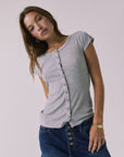 Front view of a woman wearing Chaser's heather gray button-up Anchor Tee and the Sloane Mini Skirt against a plain background