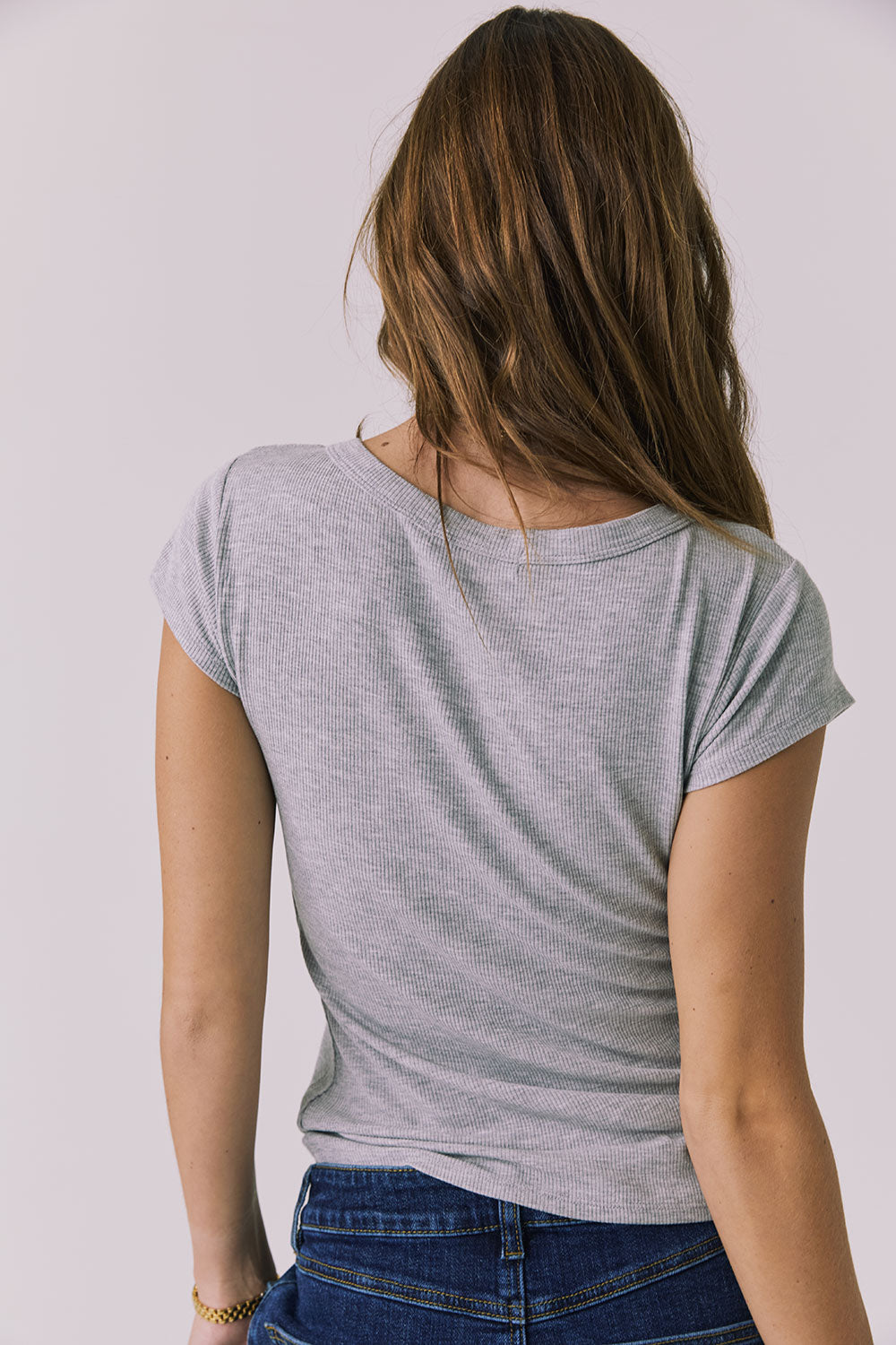Back view of a woman wearing Chaser's heather gray button-up Anchor Tee against a plain background