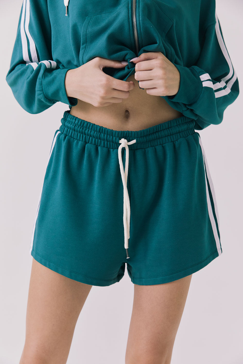 Front view of a woman wearing Chaser's Hanoverr Teal and White Shorts in a clean full body against a plain background