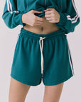 Front view of a woman wearing Chaser's Hanoverr Teal and White Shorts in a clean full body against a plain background