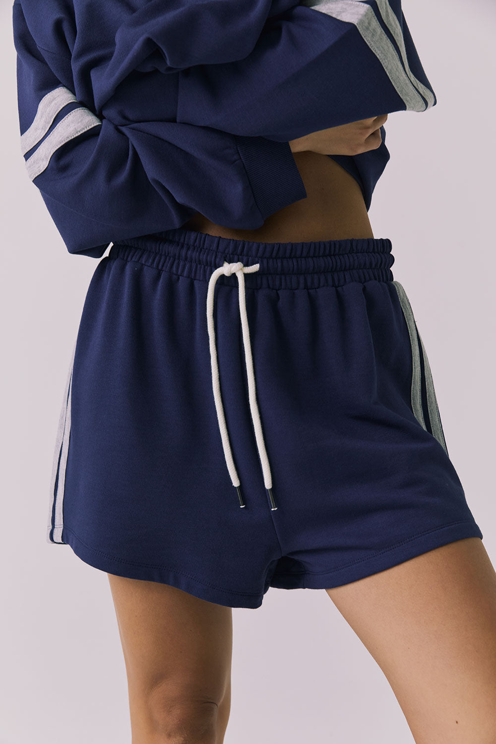 Front view of a woman wearing Chaser's navy blue Cornell Sapphire & Heather Grey Hanoverr shorts on a plain background