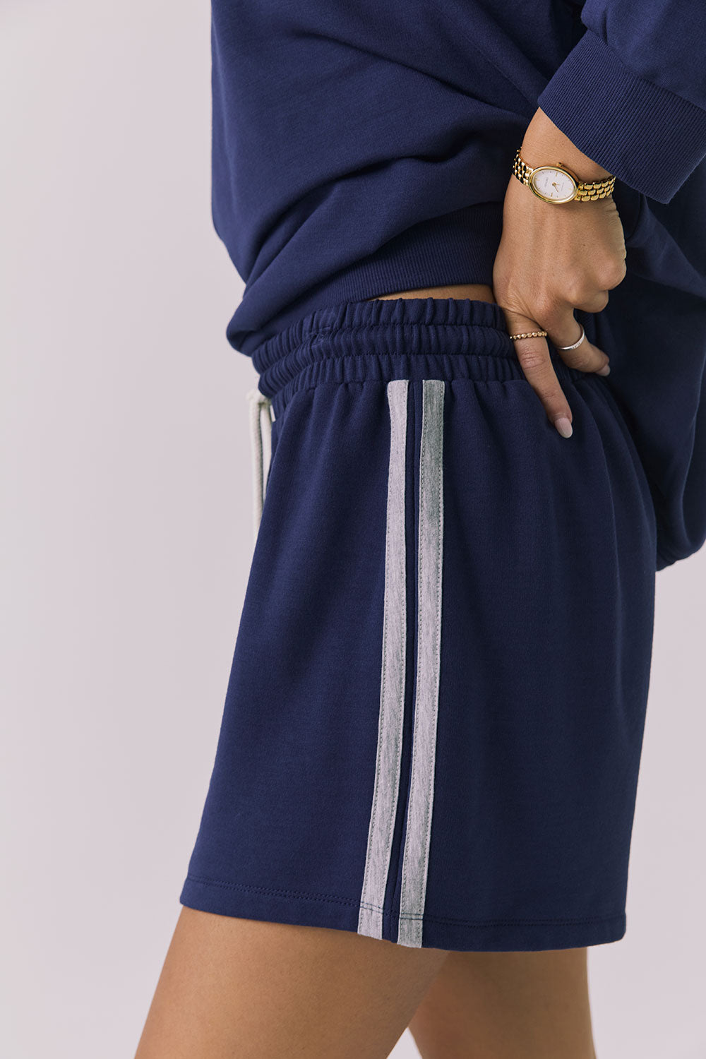 Side view of a woman wearing Chaser's navy blue Cornell Sapphire & Heather Grey Hanoverr shorts on a plain background