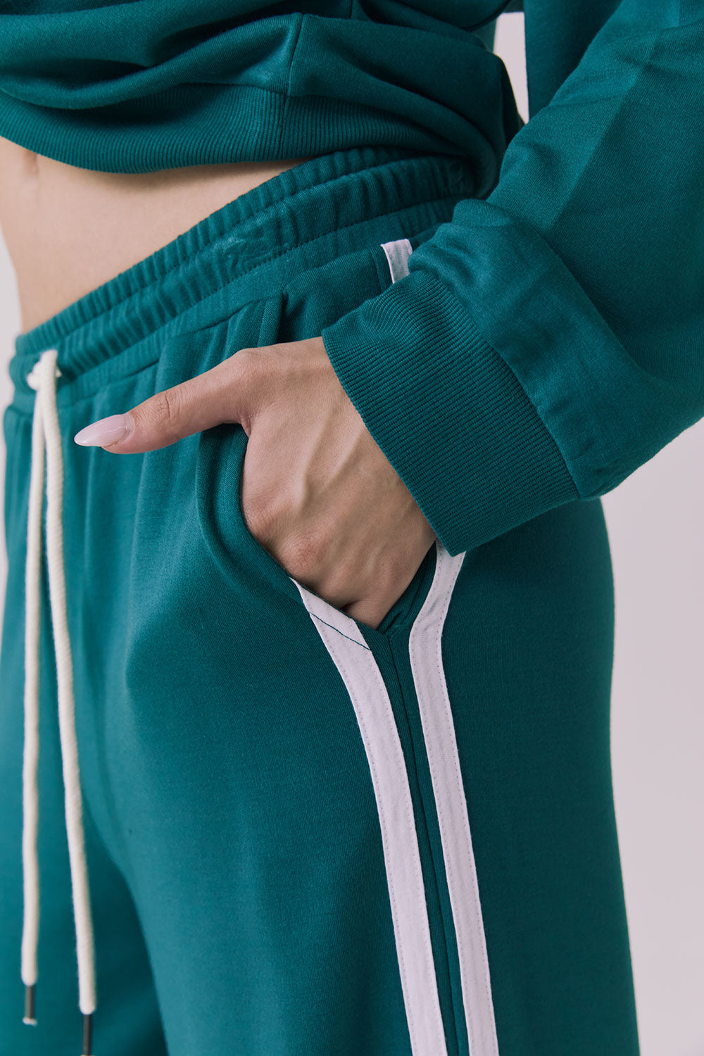 Side view of a woman wearing Chaser's Hanoverr Teal and White Shorts in a clean full body against a plain background
