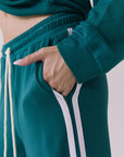 Side view of a woman wearing Chaser's Hanoverr Teal and White Shorts in a clean full body against a plain background