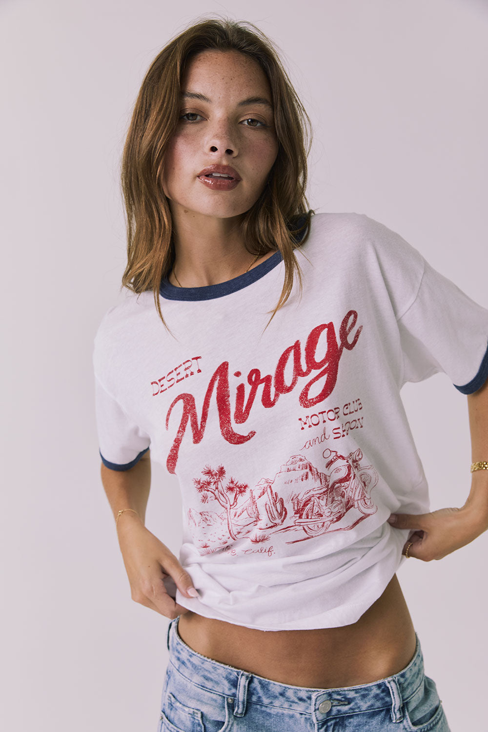 Front view of a woman wearing Chaser's white Desert Mirage Motor Club Tee with red text and graphics on a plain background