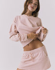 Chaser Campbell Honey Peach Pullover shown from the front with a cropped hem and ribbed trim, styled with the Soleil Mini Skort for a coordinated look