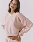Side detail view of the Chaser Campbell Honey Peach Pullover showing the cropped silhouette and cuff accents, worn with the Soleil Mini Skort