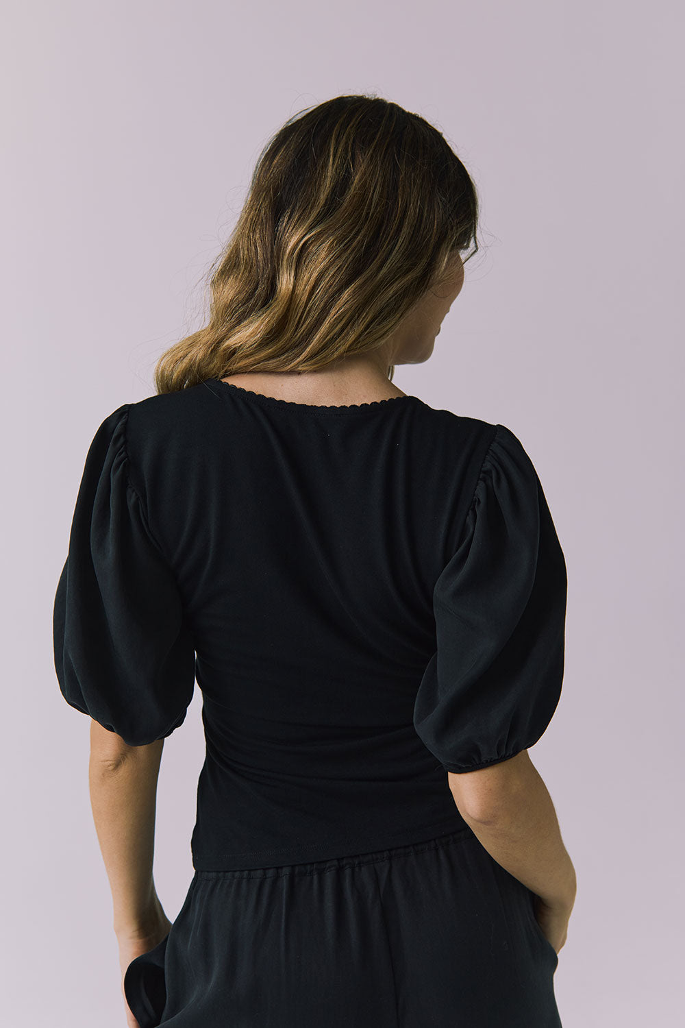 Chaser Abbie Black Blouse in a back close up capturing sleeve volume and soft drape