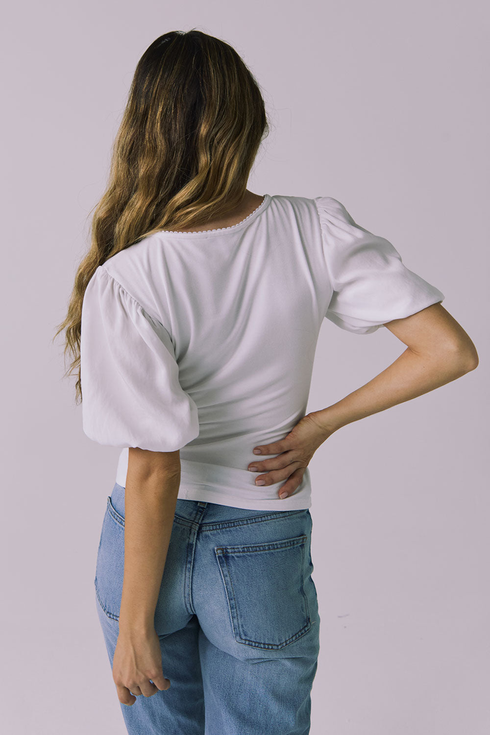 Back view of a model wearing Chaser Brands Abbie White Blouse with soft ruching and puff sleeves