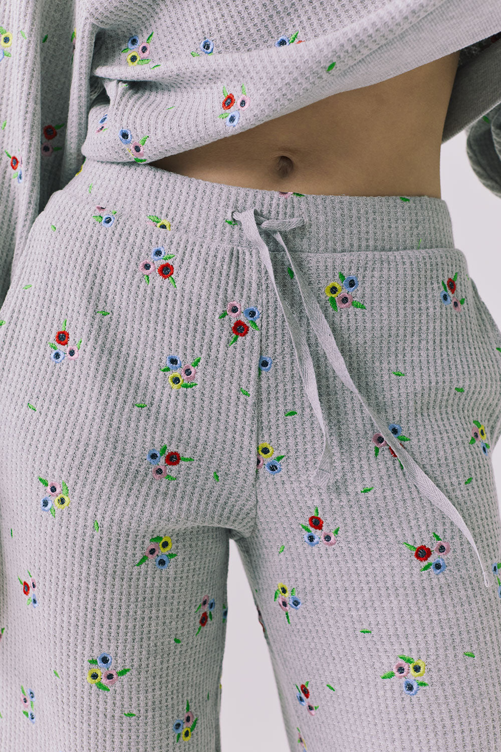 Close-up of the Chaser Brandy Heather Grey Ditsy Embroidery Crop Joggers highlighting the adjustable drawstring waist and embroidered floral details in the waffle knit fabric