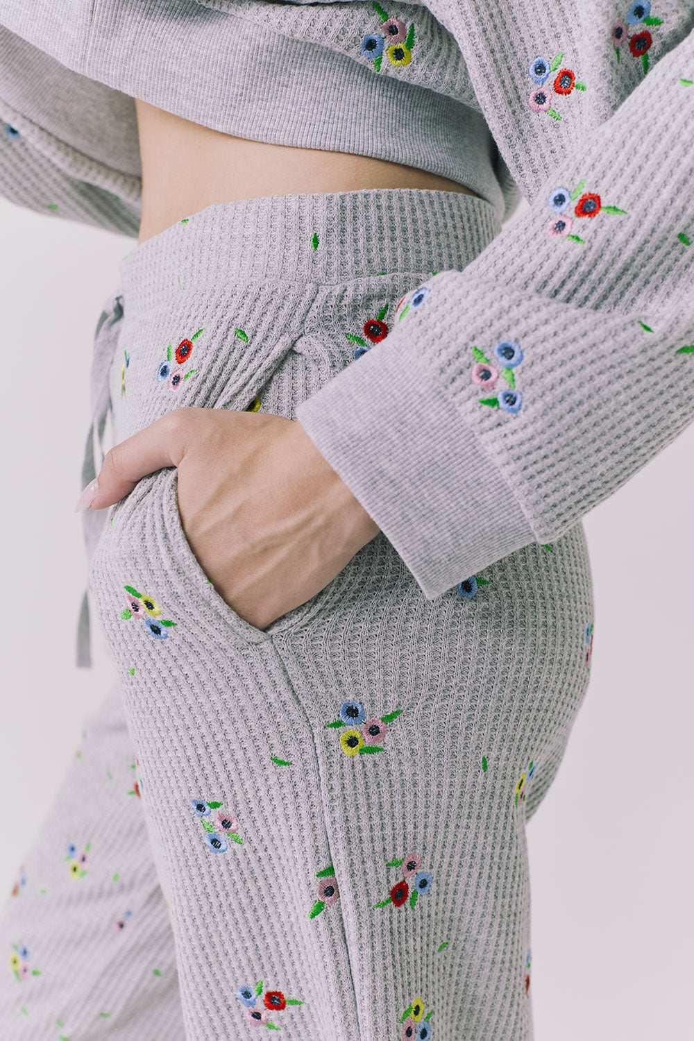 Side detail of the Chaser Brandy Heather Grey Ditsy Embroidery Crop Joggers showing a hand-in-pocket fit and ditsy embroidery on the textured waffle knit