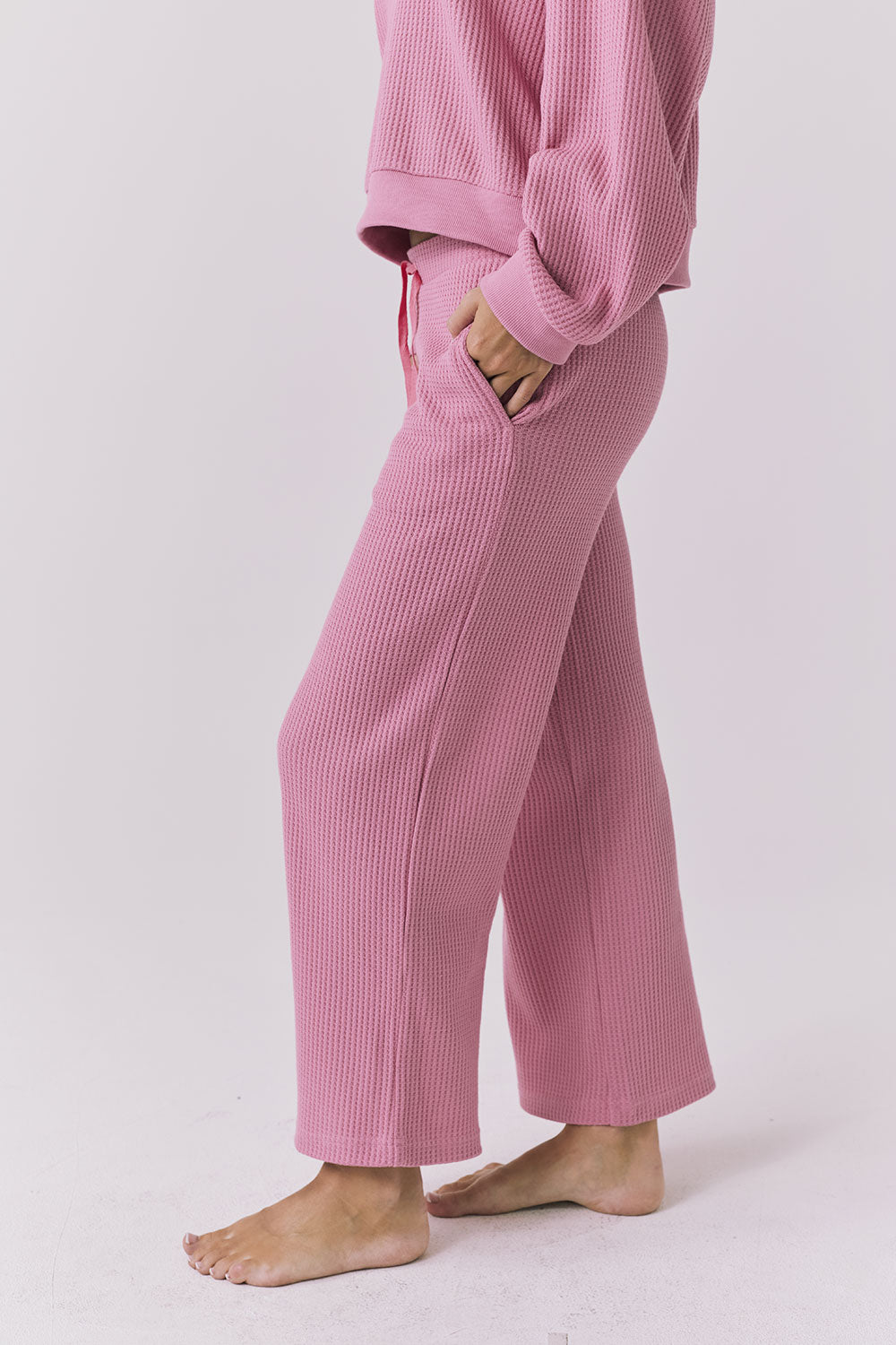 Side view of Chaser Brandy Crop Joggers in Sugar Magnolia highlighting the waffle knit fabric, side pocket detail, and relaxed lounge fit