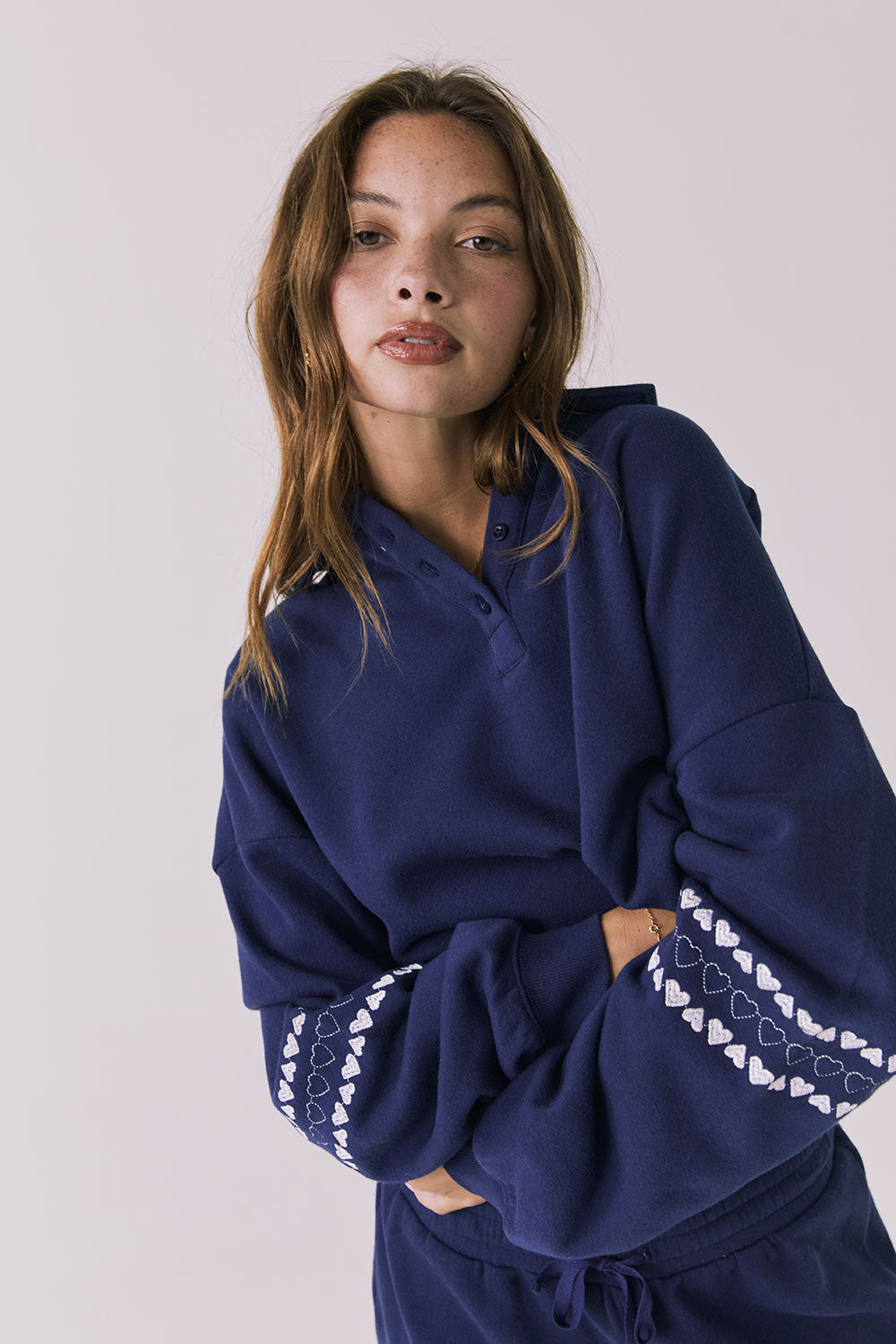 Front view of woman wearing Chaser's navy blue Heart Stitches Pullover Hoodie with arms crossed on a plain background