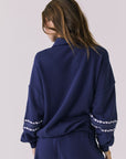 Back view of woman wearing Chaser's navy blue Heart Stitches Pullover Hoodie on a plain background