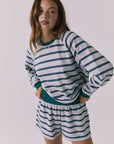 3/4 view of woman wearing Chaser's Resort Stripe Long Sleeve pullover sweater and matching shorts against a plain background