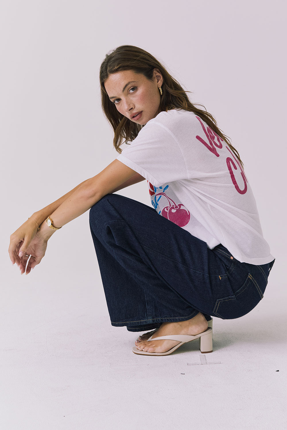 Chaser Coca-Cola Very Cherry Tee in White shown from the side in a casual seated pose, highlighting the relaxed silhouette and lightweight cotton feel from a licensed Coca-Cola collaboration