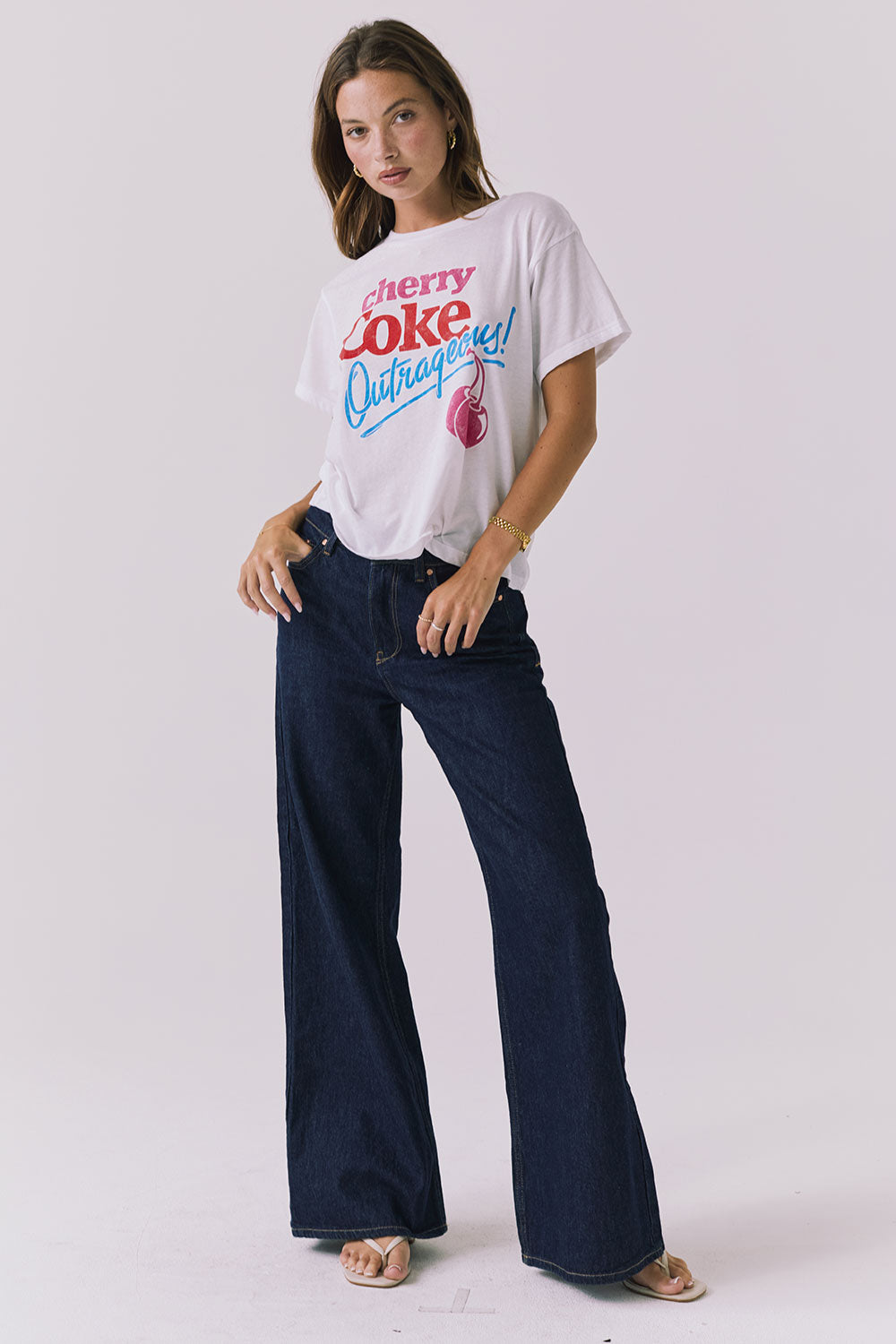 Full body view of the Chaser Coca-Cola Very Cherry Tee in White styled with classic dark denim for an effortless everyday look from a licensed Coca-Cola collaboration