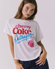 Chaser Coca-Cola Very Cherry Tee in White shown from a three-quarter angle, emphasizing the soft drape, short sleeves, and iconic front graphic from a licensed Coca-Cola collaboration