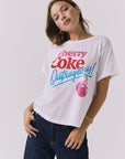 Chaser Coca-Cola Very Cherry Tee in White featuring a bold Cherry Coke “Outrageous!” graphic across the chest, styled with a relaxed drape and classic crew neckline from a licensed Coca-Cola collaboration